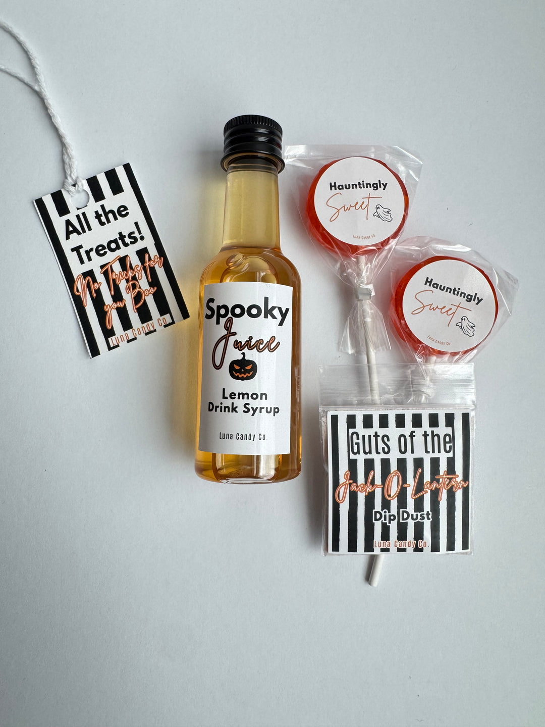 A Halloween-themed treat bundle on a light gray background, featuring a miniature bottle of &