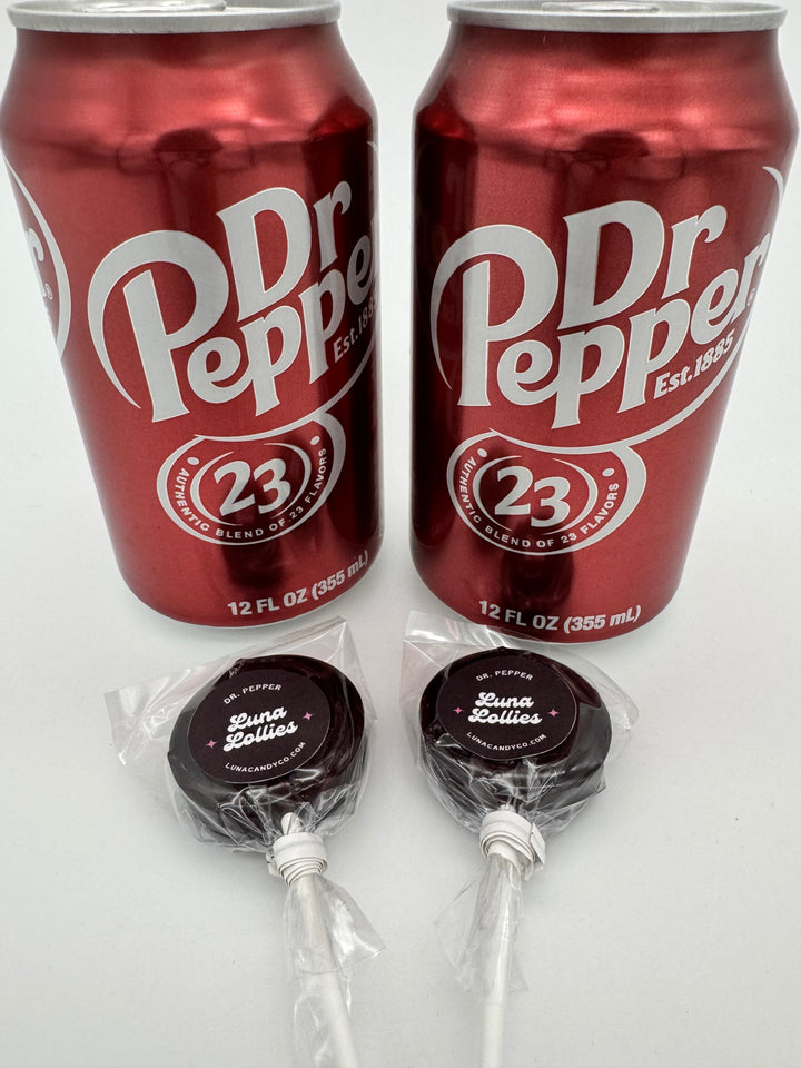 Two Dr Pepper cans and three Dr. Pepper lollipops on a white background