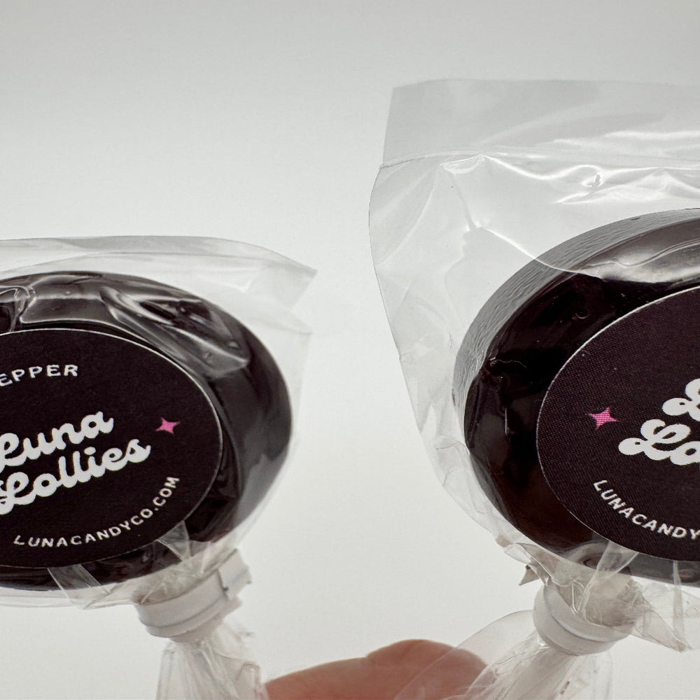 hand holding two Dr. Pepper inspired lollipop candy