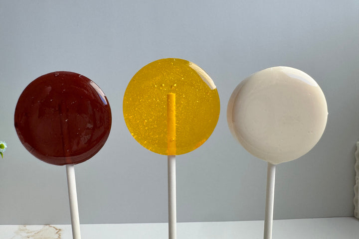 Stack of Honey Bee baby shower lollipops in yellow and white