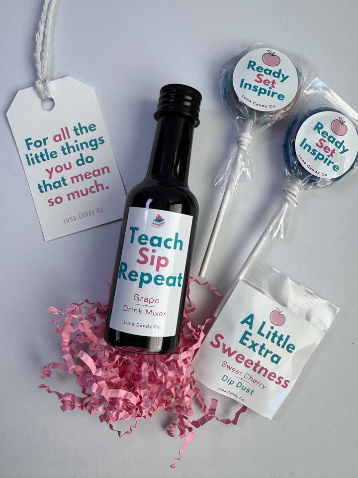 A curated gift set on a light gray background featuring a small black bottle labeled &
