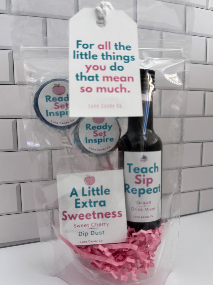 A packaged gift set in a clear bag featuring a small bottle labeled &