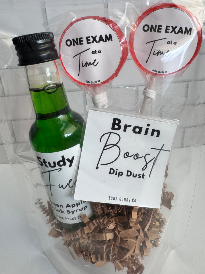A packaged study gift set from Luna Candy Co. featuring a small green bottle of apple cinnamon syrup, two lollipops labeled &