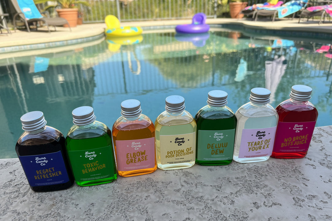Assorted small bottles of luna candy drink syrup with colorful liquids near a swimming pool for summer drink party
