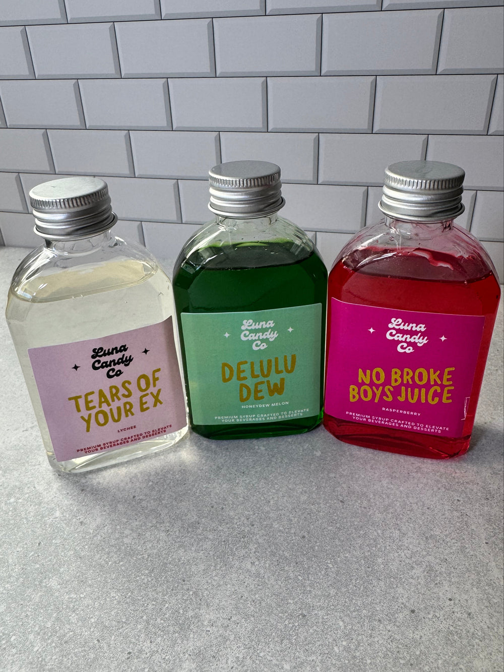 Three small drink mix bottles with colorful labels on a tiled surface