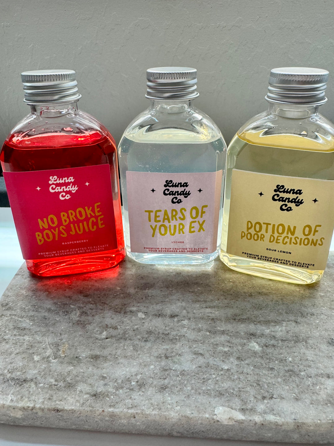 Three small drink mix bottles with colorful labels on a gray surface