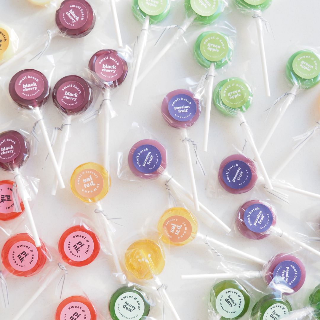 A variety of colorful lollipops with different flavors, each on a stick, wrapped in individual clear wrappers. Best selling flavors