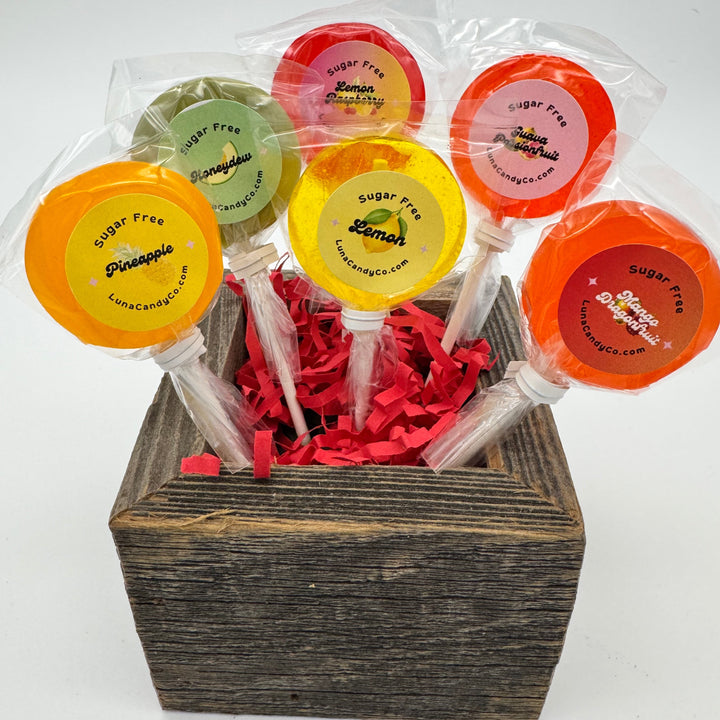 Colorful sugar free lollipops in clear packaging with a wooden box on a white background